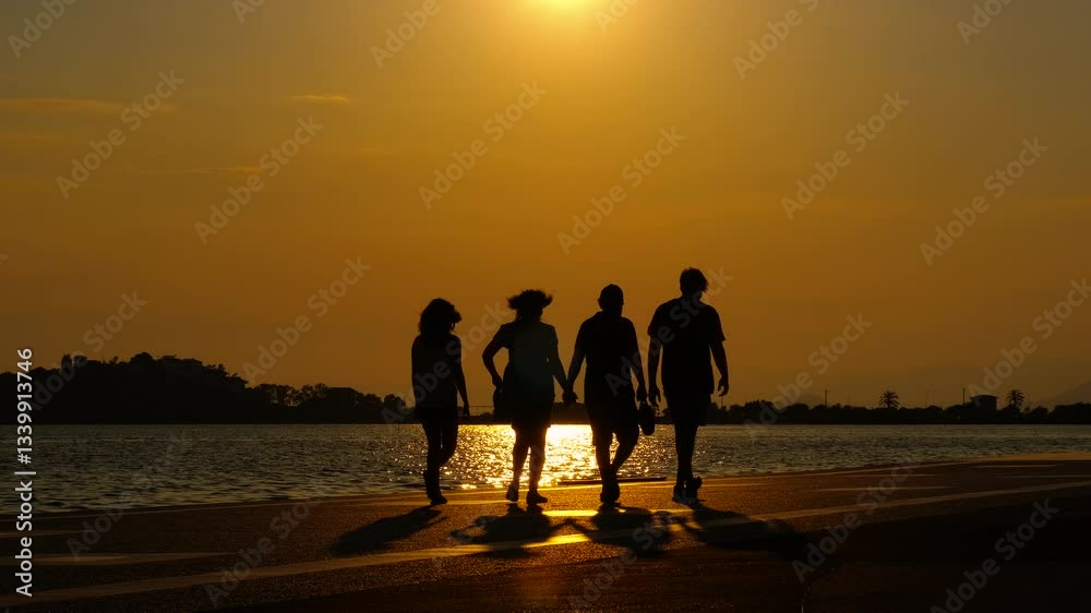Friends silhouette relax on nightfall shore. A view of friends silhouettes have a promenade on the sea shore against sunset time. Friends silhouette relax on nightfall shore. A view of friends silhouettes have a promenade on the sea shore against sunset time.