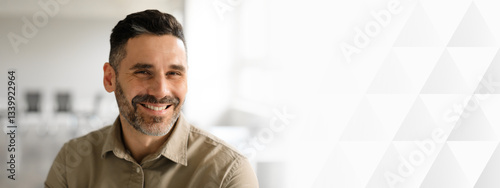 Fotografija A middle aged businessman with a beard is smiling while seated in a modern office