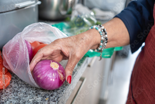 Wallpaper Mural Senior woman taking red onion from plastic bag in kitchen Torontodigital.ca