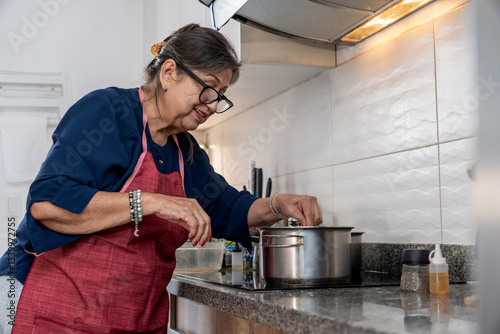 Senior hispanic woman cooking lunch in kitchen