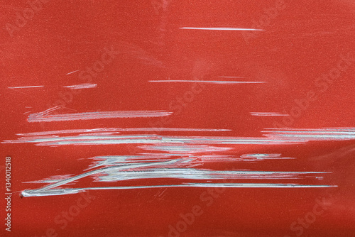 Close up of a red car with multiple visible scratches and paint damage The scratches expose the underlying metal, creating a contrast against the glossy surface. Perfect for automotive damage concepts