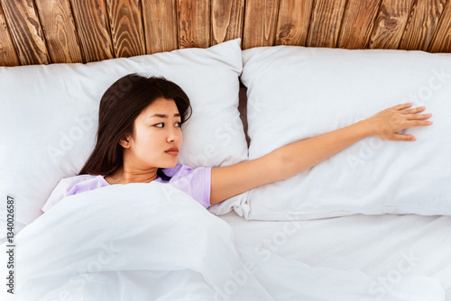 Depressed Asian Woman After Divorce Touching Empty Pillow Suffering From Loneliness Lying Alone In Bed In Bedroom After Breakup. Top-View