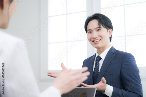 お客様に説明する若手の営業マンなどのイメージ