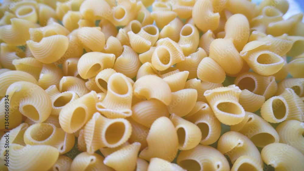 Pasta in close-up.Close-up of a raw fluted paste in the shape of horns. Delicious pasta of light golden color, stacked in a chaotic manner, emphasize the texture and shape of the product. Pasta in close-up.Close-up of a raw fluted paste in the shape of horns. Delicious pasta of light golden color, stacked in a chaotic manner, emphasize the texture and shape of the product.