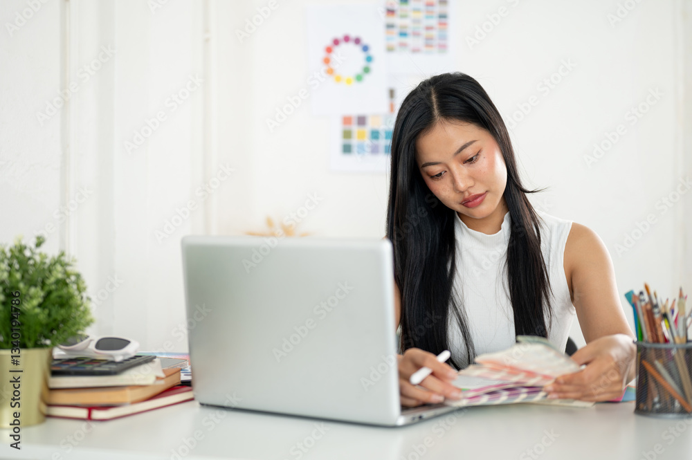 An asian woman is looking and choosing color from the printed color charts or color palette in hand An asian woman is looking and choosing color from the printed color charts or color palette in hand