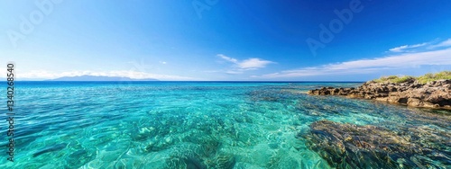 Clear Blue Ocean Water with Rocky Shoreline under Bright Sky