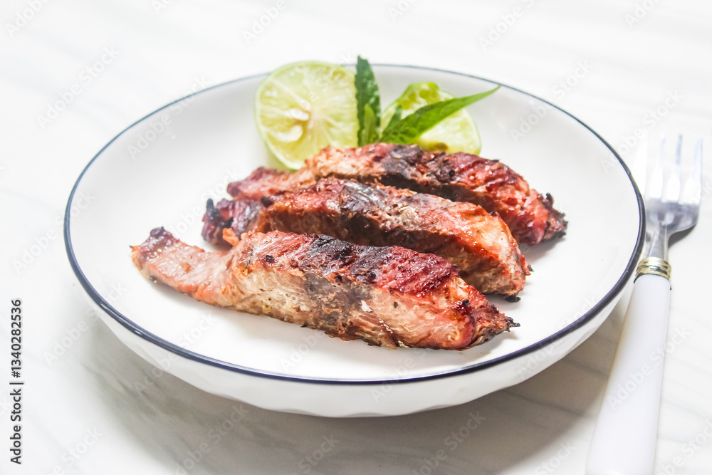 grilled fish slices and lime on a plate, with spoon and fork beside grilled fish slices and lime on a plate, with spoon and fork beside