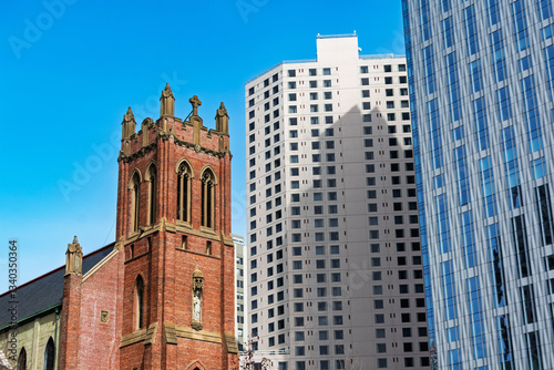 St. Patrick Catholic Church with red brick walls and pointed arches, stands prominently alongside modern high-rise skyscrapers in San Francisco South of Market district