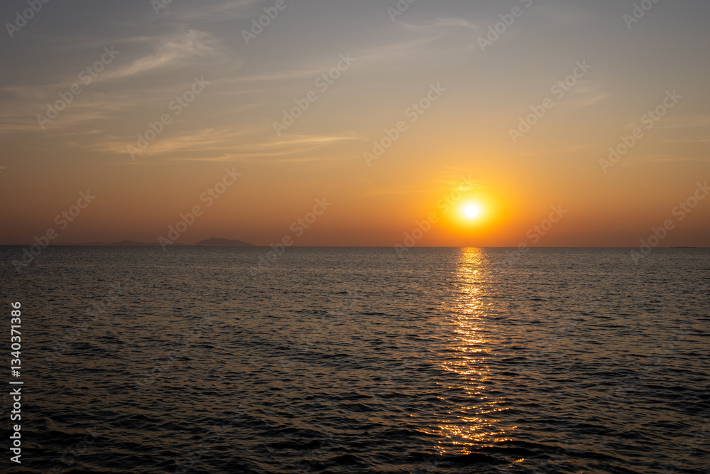 Obraz premium serene sunset view over the ocean, with the sun casting a warm golden reflection