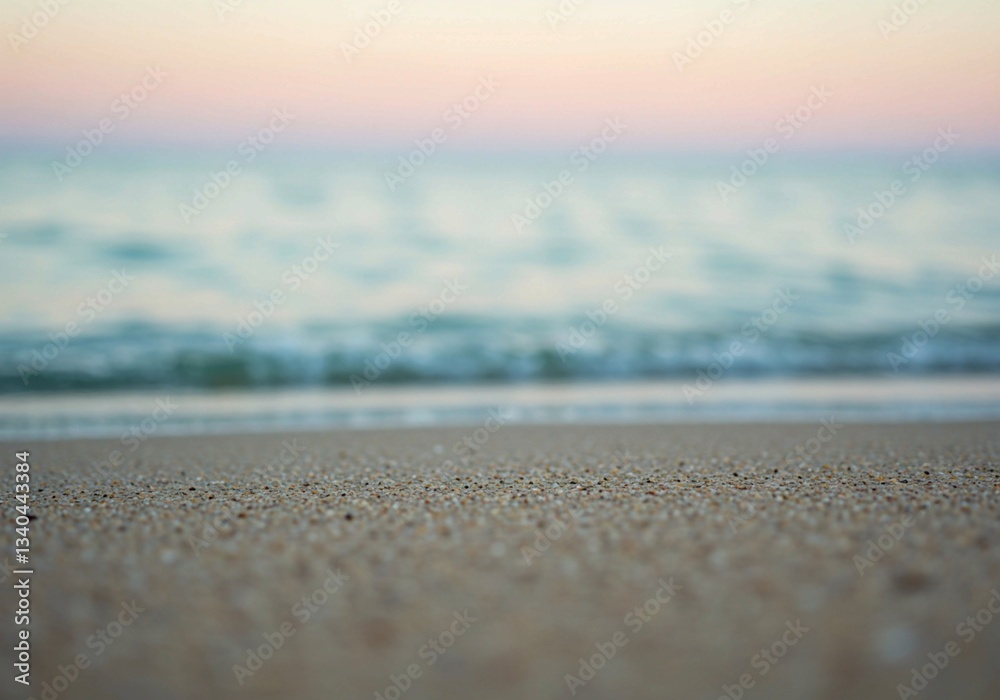 The image captures sandy beach texture close-up with a blurred ocean background in warm golden light, creating a tranquil scene The image captures sandy beach texture close-up with a blurred ocean background in warm golden light, creating a tranquil scene