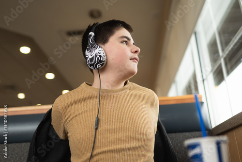 Obraz na plátne Teen boy looks out window with headphones on