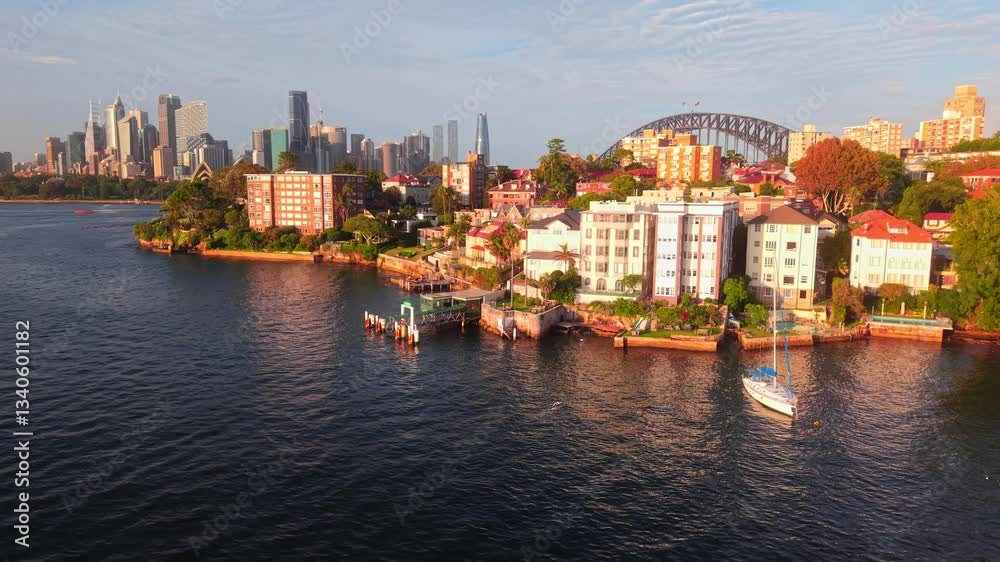 Breathtaking aerial rising up to reveal the Sydney skyline and waterfront at sunrise, orange glow on buildings, with opera house Breathtaking aerial rising up to reveal the Sydney skyline and waterfront at sunrise, orange glow on buildings, with opera house