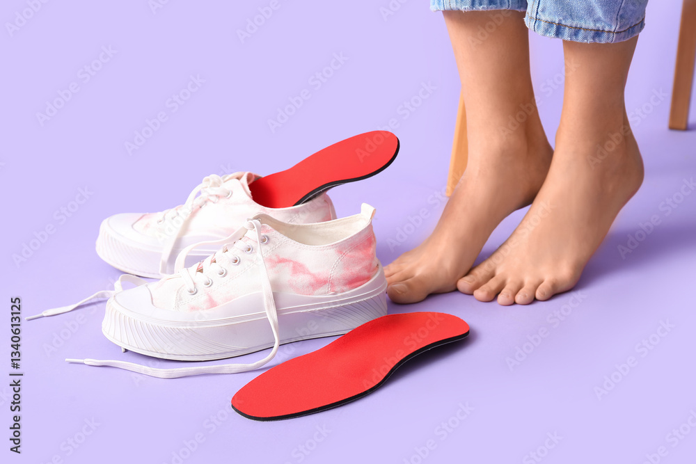 Naklejka premium Female legs near orthopedic insoles and sneakers on lilac background, closeup