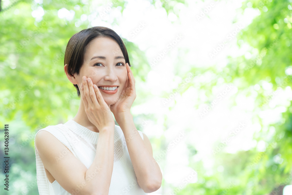 新緑の中でスキンケアをするミドルの女性
