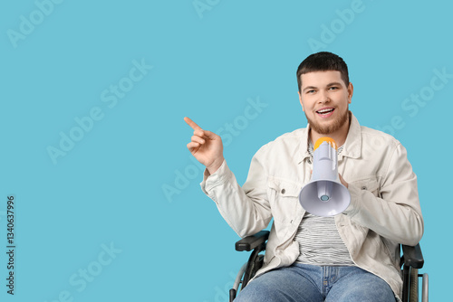 Young man in wheelchair with megaphone pointing at something on blue background
