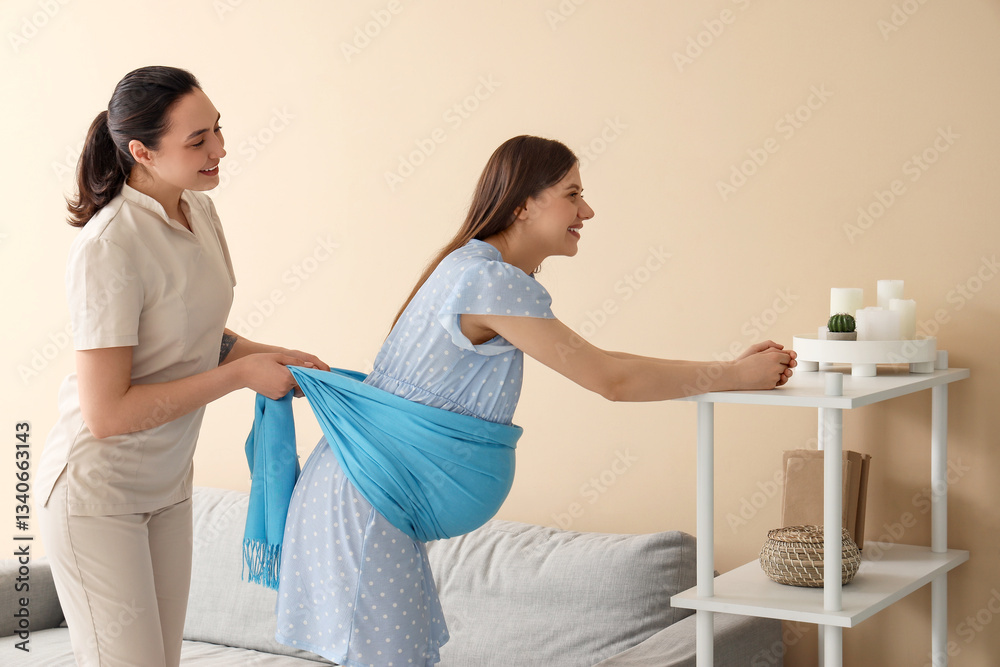 Fototapeta premium Young pregnant woman getting massage from doula at home