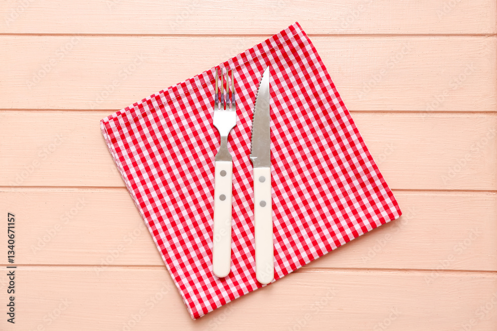 Table setting with napkin, fork and knife on beige wooden background Table setting with napkin, fork and knife on beige wooden background