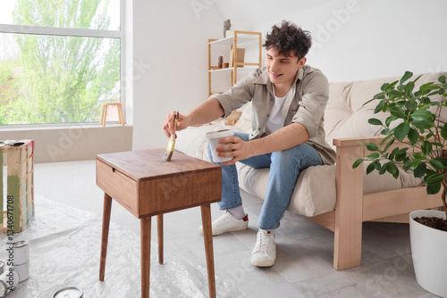 Young man painting wooden t...