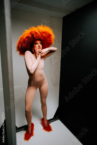 Εκτύπωση καμβά Model poses in striking orange feathered headpiece and bodysuit inside studio se