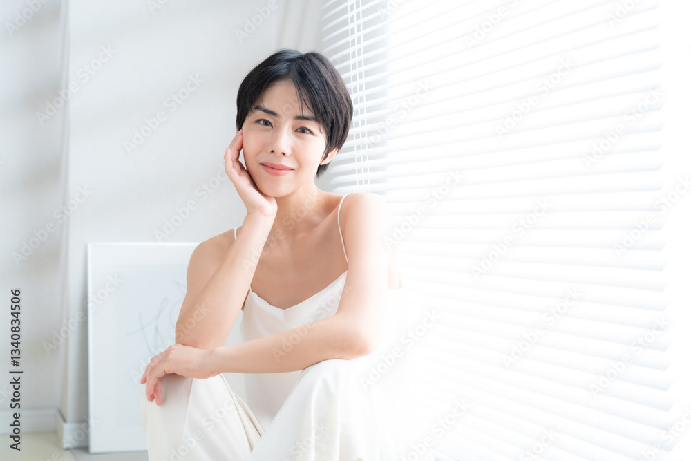 窓際でスキンケアをする若い女性 窓際でスキンケアをする若い女性