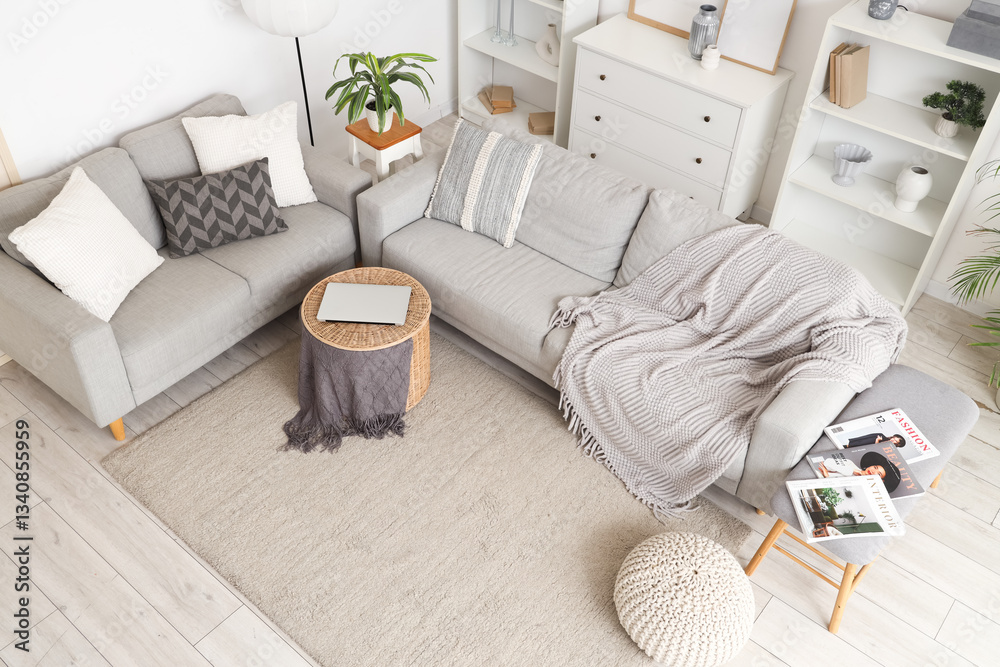 Fototapeta premium Interior of light living room with grey sofas, soft bench and shelf units, top view