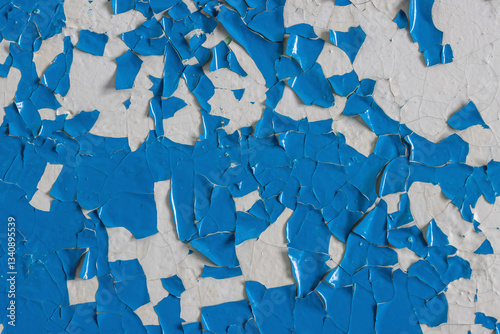 Blue peeling paint on the wall. Old concrete wall with cracked flaking paint. Weathered rough painted surface with patterns of cracks and peeling. High resolution texture for background and design.