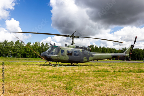 Green camouflaged army helicopter parked on the grass