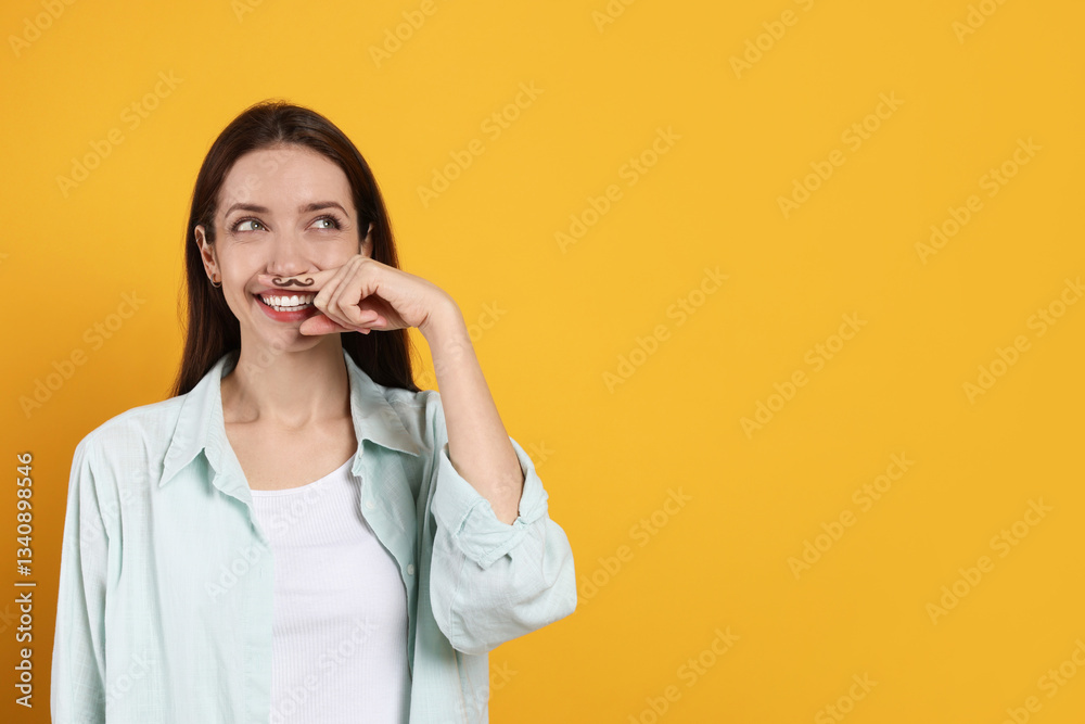 Happy woman holding finger with drawn mustache above lips on orange background. Space for text Happy woman holding finger with drawn mustache above lips on orange background. Space for text