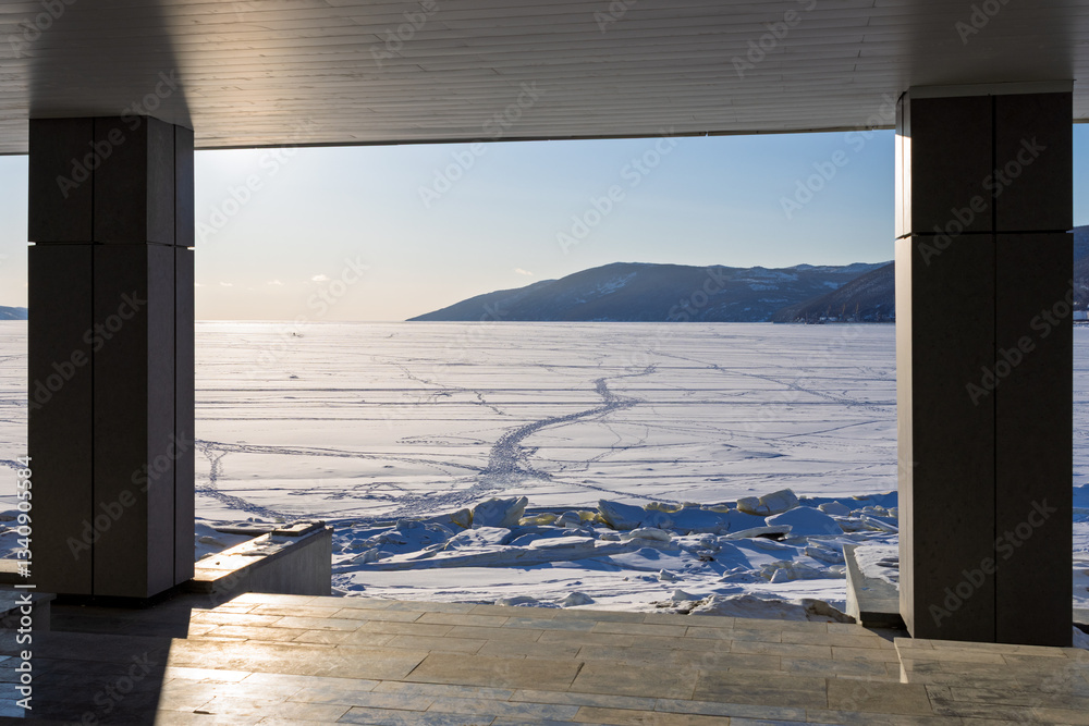 Beautiful view of the ice-covered sea bay. In the foreground are the columns of the building located on the seashore. Embankment of Nagaev Bay, Magadan city, Magadan region, Russian Far East.