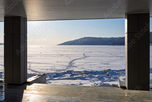 Obraz na płótnie Beautiful view of the ice-covered sea bay. In the foreground are the columns of the building located on the seashore. Embankment of Nagaev Bay, Magadan city, Magadan region, Russian Far East. w salonie