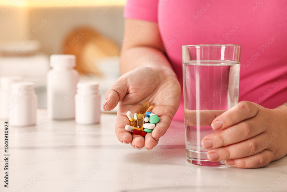 Plus size woman holding pile of weight loss supplements and glass with water at marble countertop in kitchen, closeup. Space for text Plus size woman holding pile of weight loss supplements and glass with water at marble countertop in kitchen, closeup. Space for text