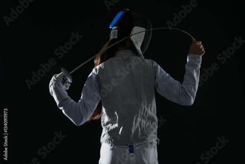 Fencer with epee on black background, back view