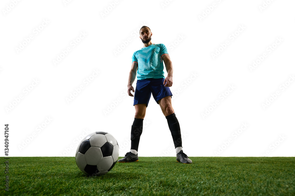 Obraz premium Low-angle view of football player standing over ball on green field, exuding confidence and dominance before action. Concept of leadership, tournament anticipation, sport, championship moment.