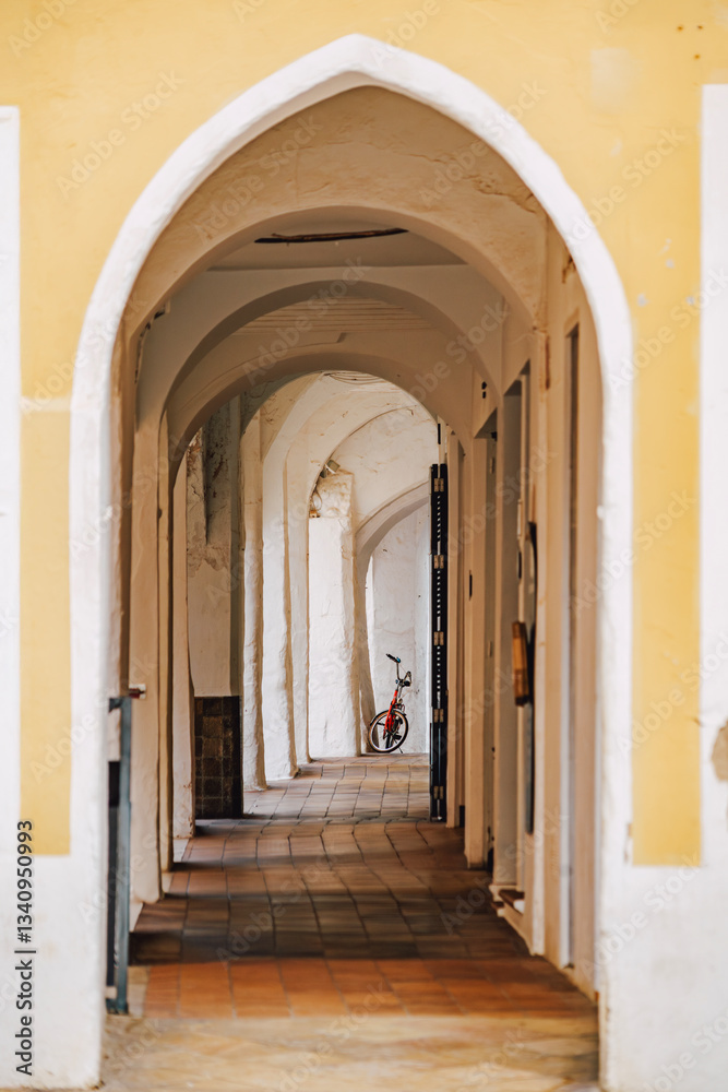 Explore the hidden charm of Ciutadella with this image of an arched passage, featuring architectural arches, a tiled floor, and a distant bicycle. Ideal for travel, culture, and architectural themes