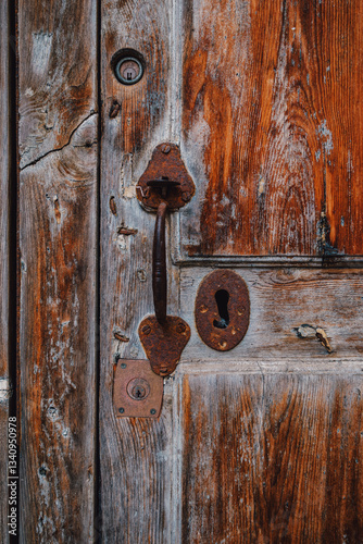 Obraz na płótnie A close-up view of an old wooden door with weathered textures and rusty hardware, showcasing timeworn beauty and rustic charm. Ideal for vintage, architectural, and texture-themed projects w salonie