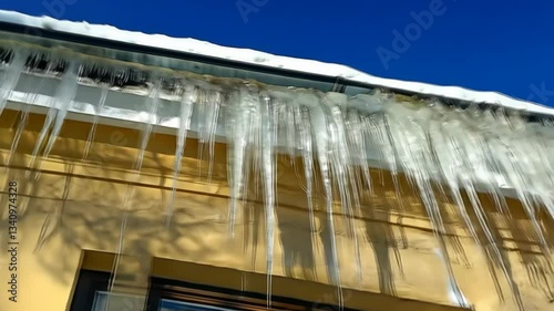 Long icicles hanging from the eaves of a house on a sunny winter day