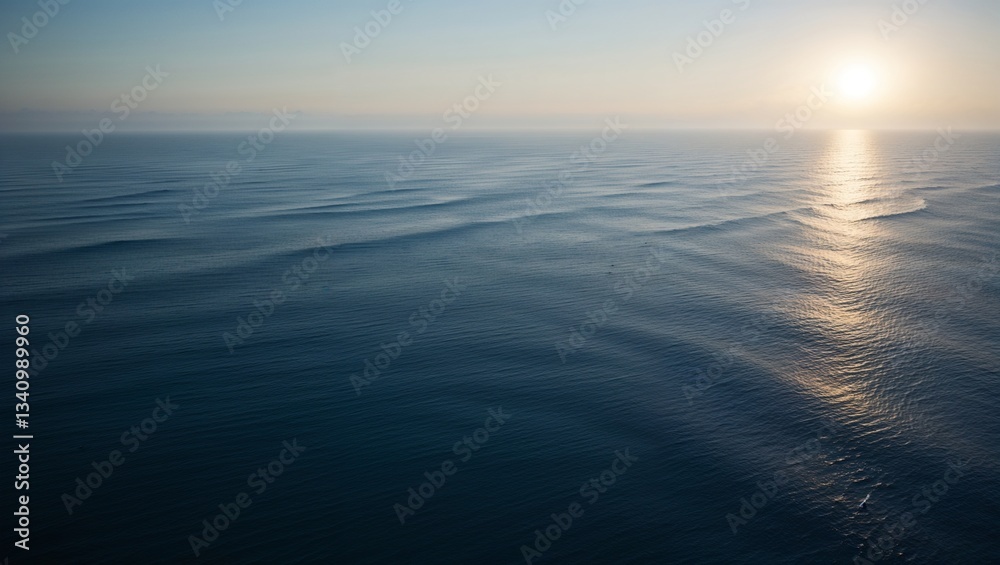 Obraz premium Rippling ocean waves reflect the warm colors of a peaceful sunset.