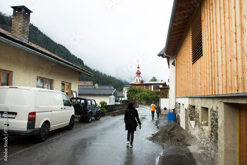 Fototapeta Naklejka Na Ścianę i Meble -  Travelers people walking in small alley go to Kath Pfarramt church at Pfunds village in Tyrol, Austria