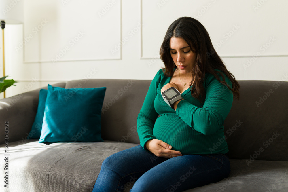 Concerned pregnant woman using a portable blood pressure monitor at home, taking care of her health during pregnancy Concerned pregnant woman using a portable blood pressure monitor at home, taking care of her health during pregnancy