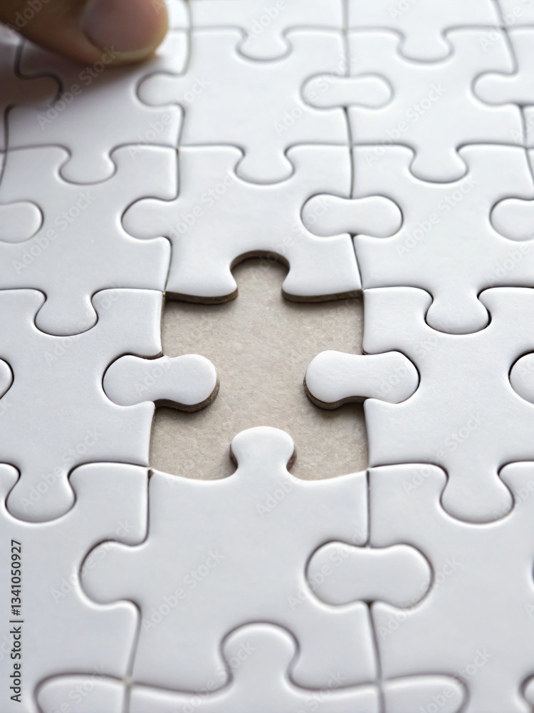 Hand Completing Puzzle with Missing Piece in White Jigsaw on Table Surface Close Up Hand Completing Puzzle with Missing Piece in White Jigsaw on Table Surface Close Up