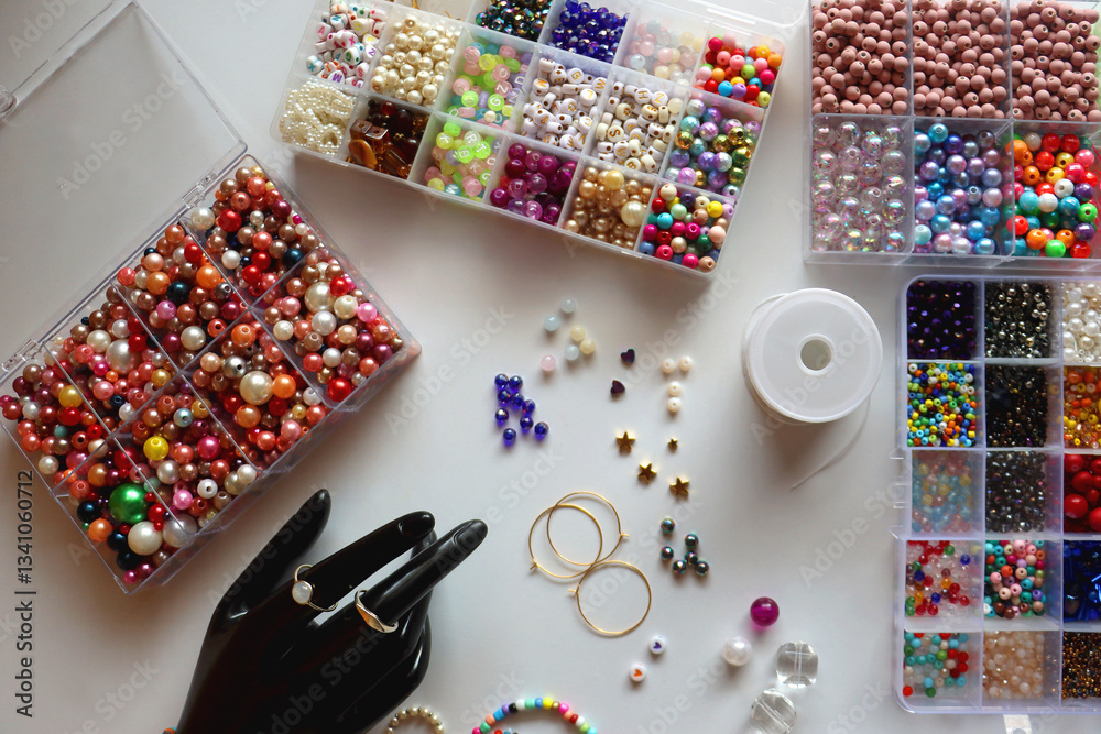 Hand figurine, colorful friendship bracelets, necklaces, various beads and DIY supplies on the table. Making jewelry at home. Flat lay.