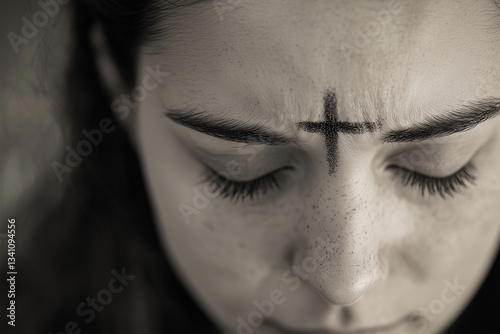 Ash Wednesday. Close-up of a woman with her eyes closed, ash cross marked on her forehead 