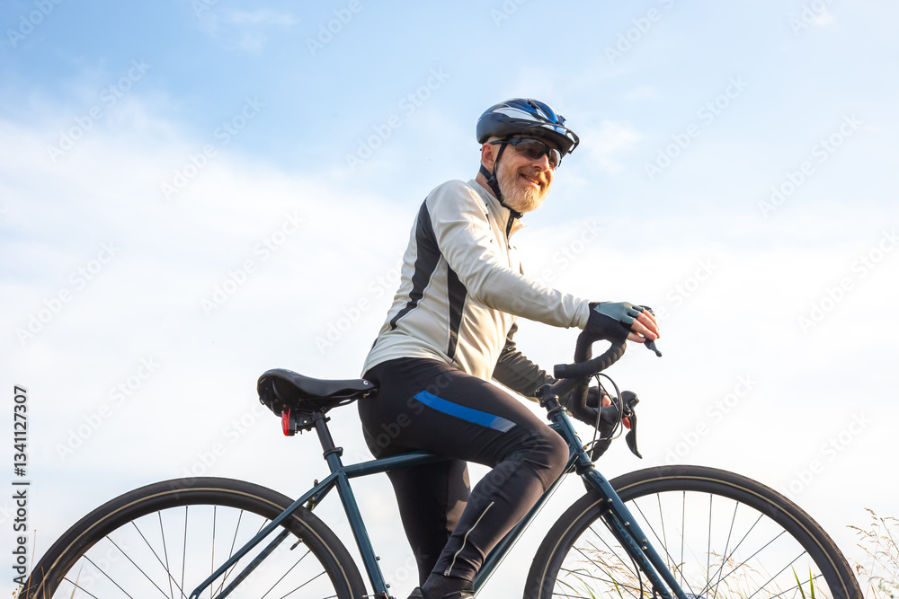 Obraz premium Bearded man cyclist stands with a bike against the blue sky. cycling and health hobbies