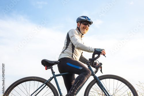 Bearded man cyclist stands with a bike against the blue sky. cycling and health hobbies
