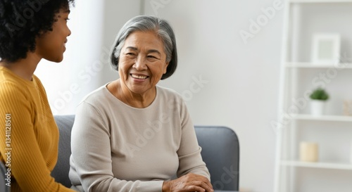 Elderly asian woman and young african female engaging in friendly conversation indoors