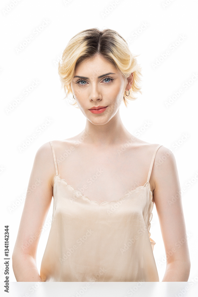 A young blonde girl with clear skin in a satin top. Beauty portrait of a woman on a white background in the studio.
