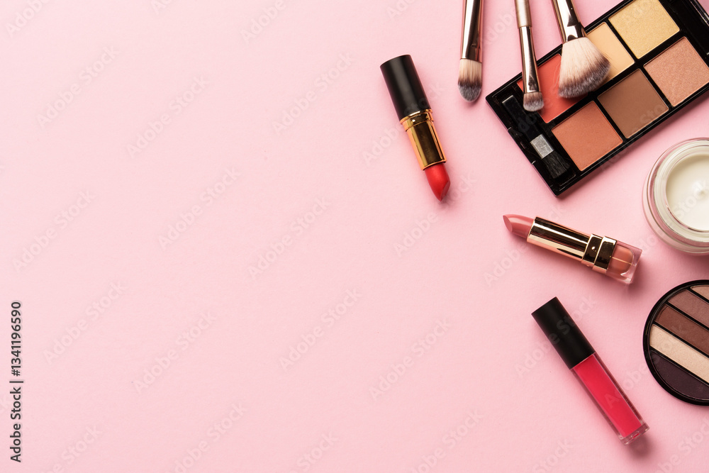 Makeup products flat lay background on pink. Eyeshadow, highlighter, cream, lipsticks and cosmetic brushes.