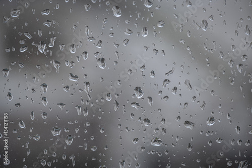Raindrops on window glass surface. Blurred background.