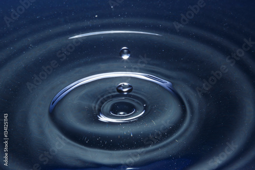 Принти на полотні Ripples form on the surface of deep blue water as a droplet impacts and creates