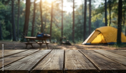 Fototapeta Naklejka Na Ścianę i Meble -  Sunlit campsite with yellow tent and wooden table in forest setting.